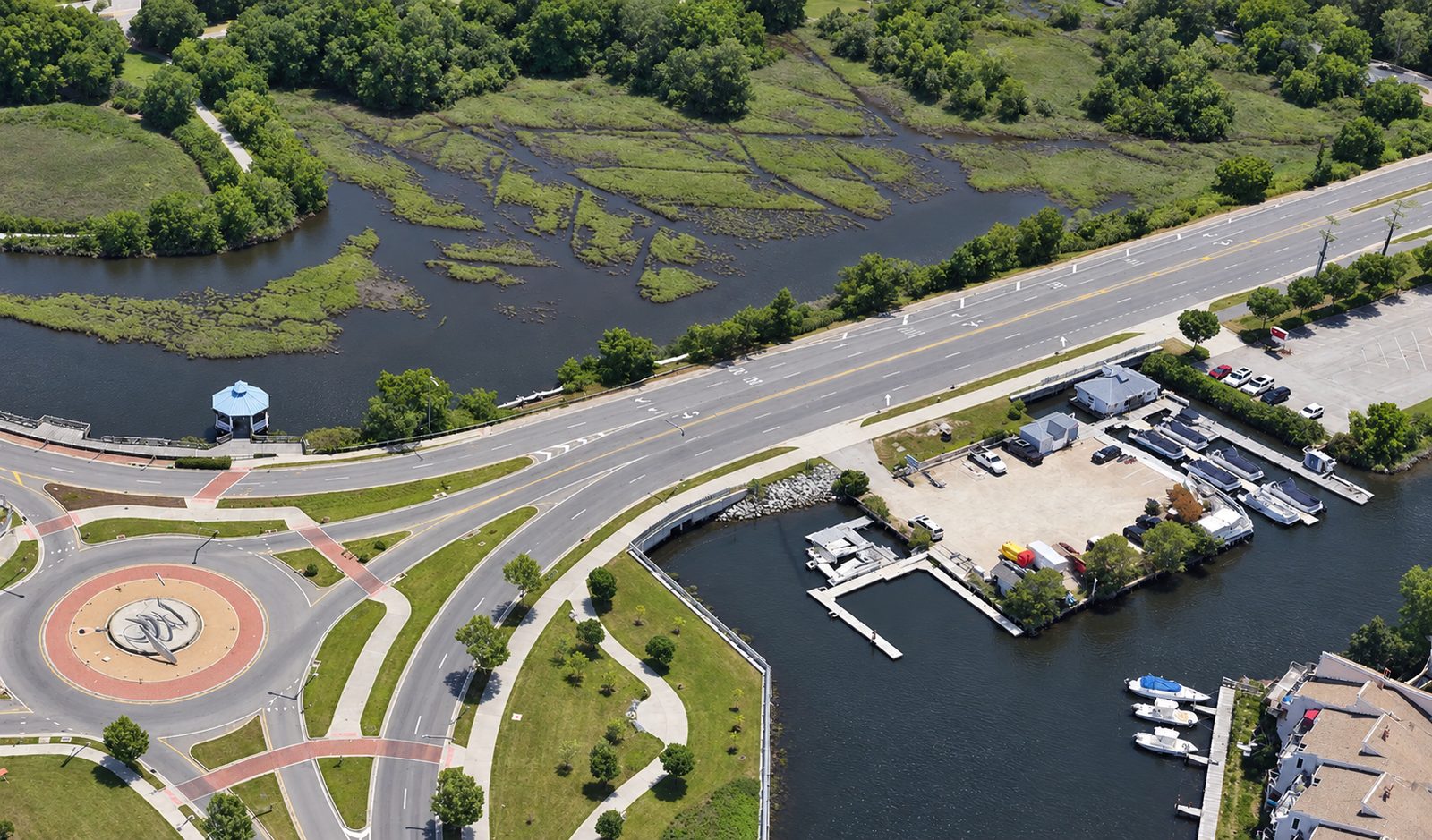 Aerial view of a multi-lane roadway and traffic circle built along a waterway corridor